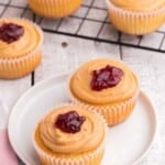 two cupcakes topped with peanut butter frosting and a dollop of jelly on a small white plate