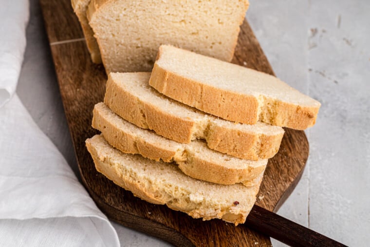 Overhead view of sliced sandwich bread on a wooden cutting board.