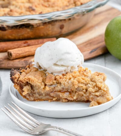 close up on a slice of dutch apple pie with ice cream and cinnamon sticks