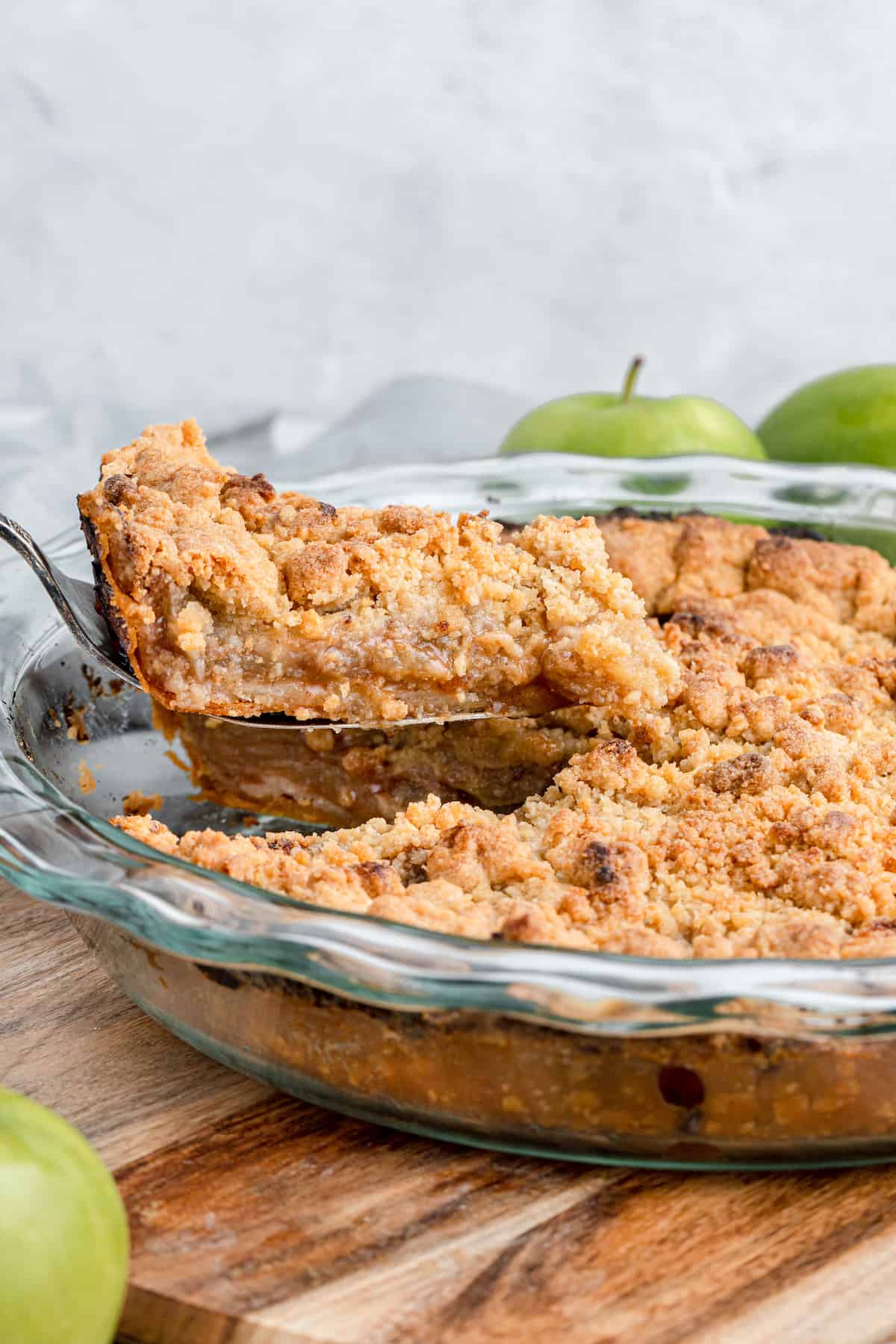 slice of gluten-free apple pie being removed from a glass pie plate