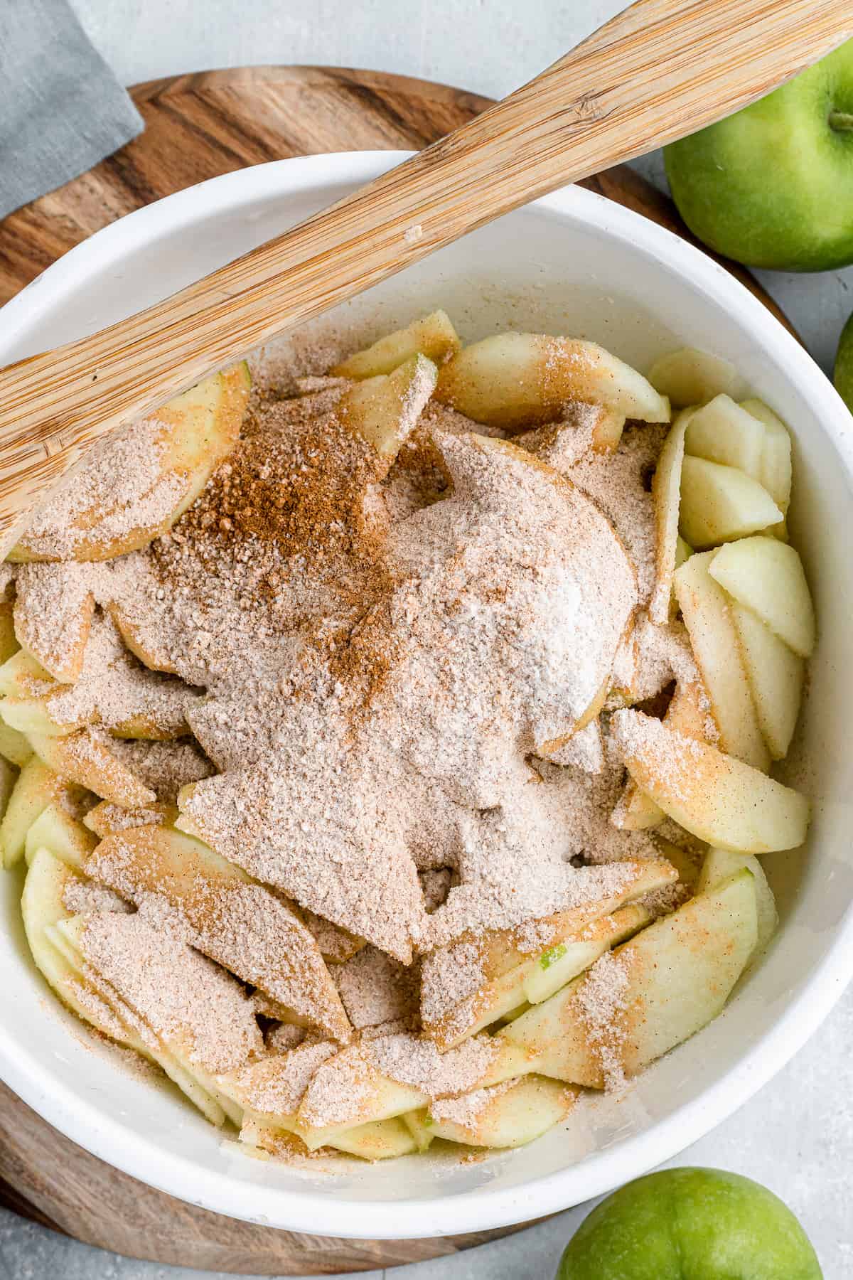 mixing bowl with sliced apples, sugar, cinnamon, flour and salt on top