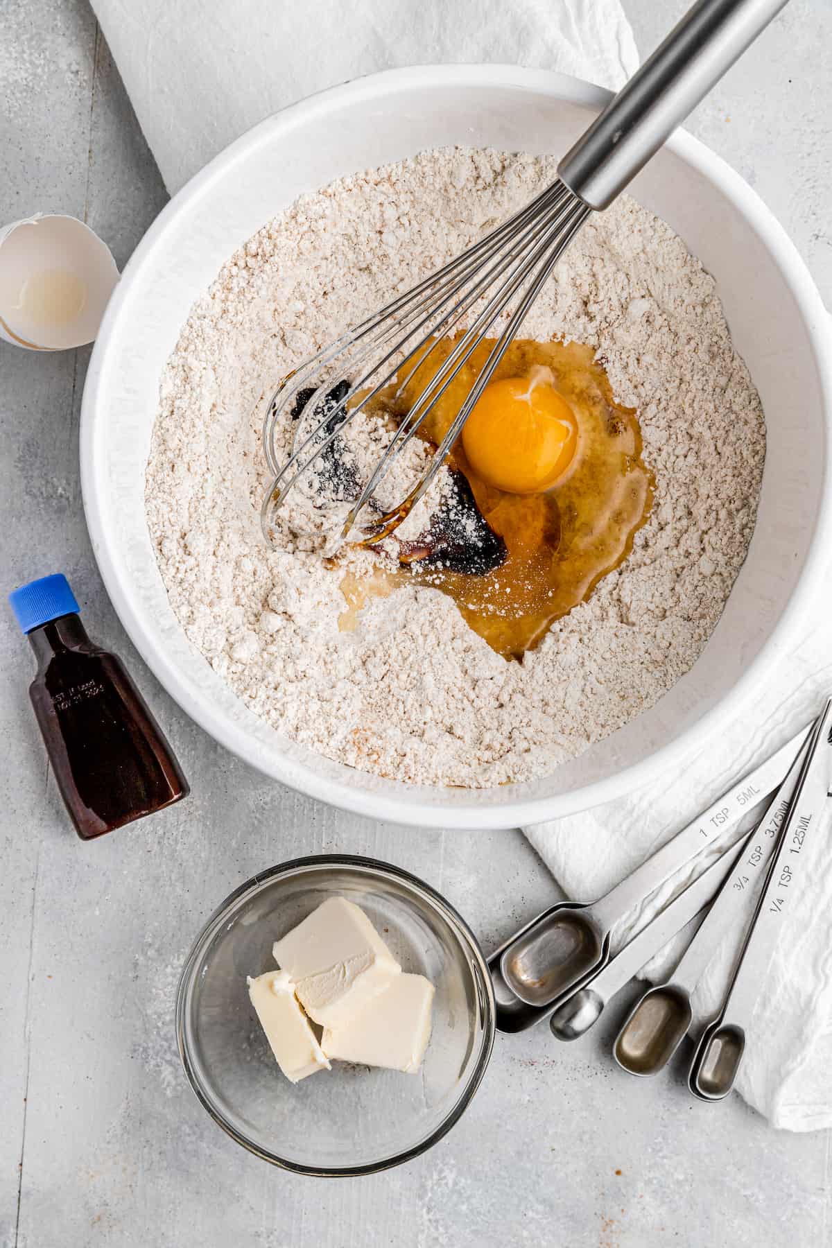 whisking eggs and vanilla into the dry ingredients in a white mixing bowl