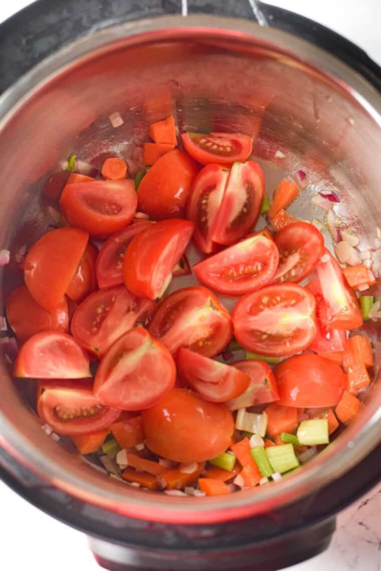 tomatoes, carrots, celery, and onion sauteeing in butter in an instant pot