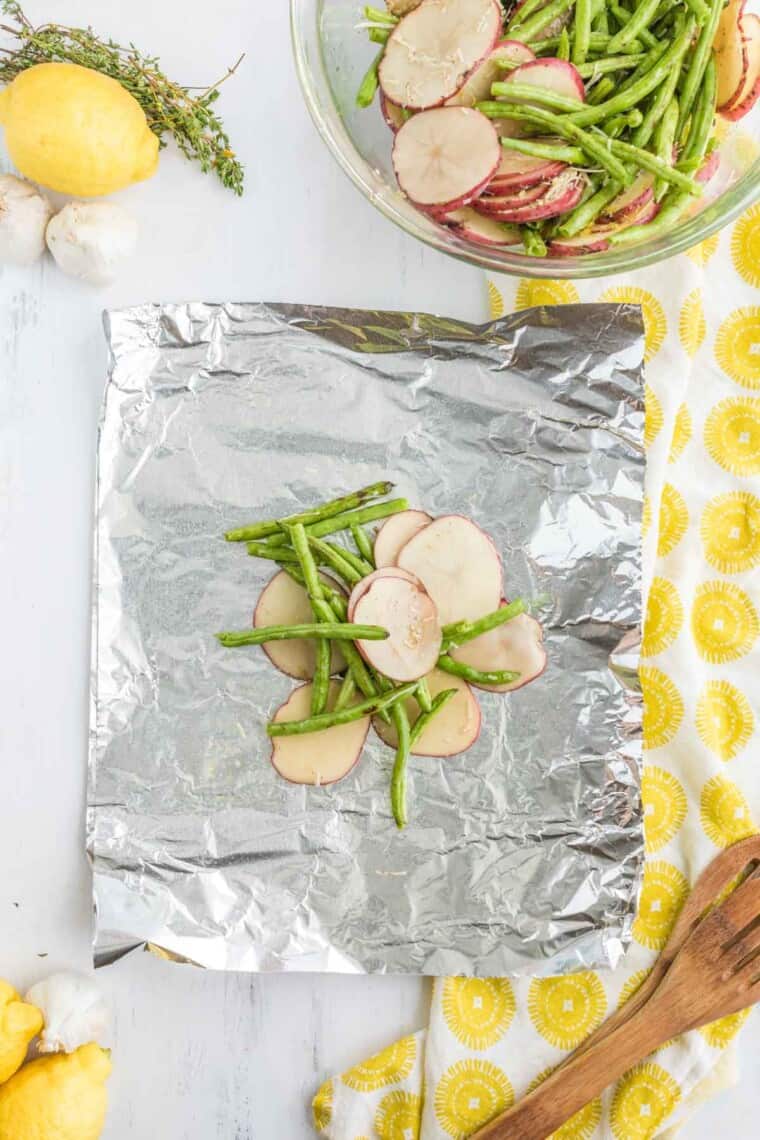 green beans and sliced potatoes on a piece of aluminum foil