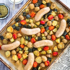 A sheet pan with roasted turkey sausage, potatoes, tomatoes, and zucchini.