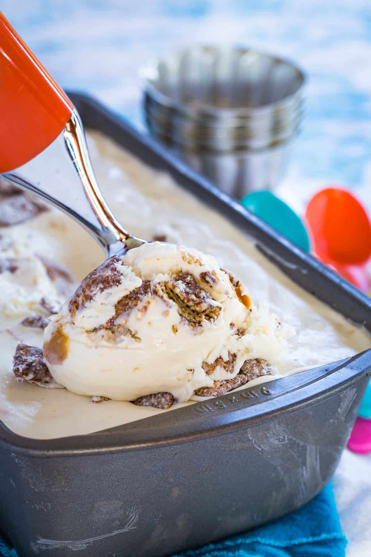 a scoop of puppy chow ice cream being scooped out of a loaf pan