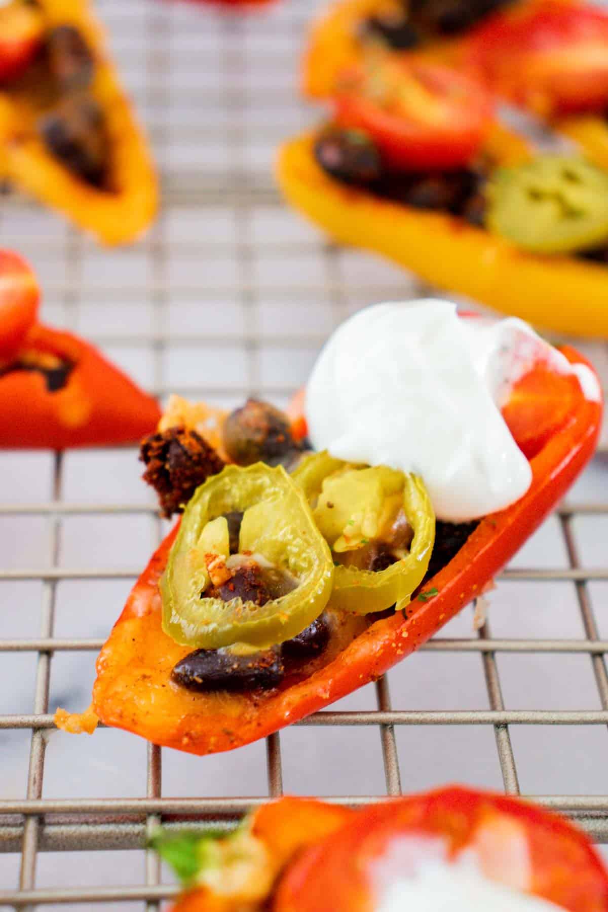 one half of a red mini bell pepper filled with beans, jalapenos, melted cheese, and sour cream