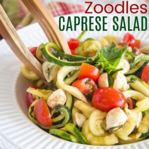 caprese zoodles salad being picked up with wooden tongs