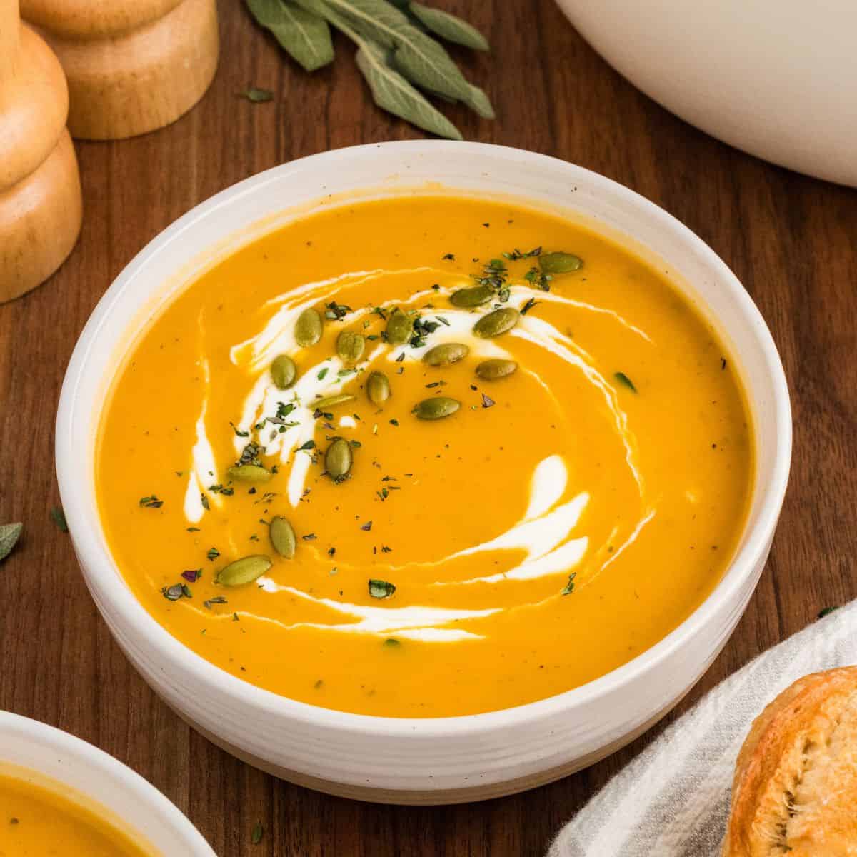 A bowl of butternut squash soup with cream and fresh herbs