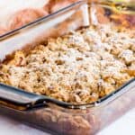 apple crisp with crumbly oat topping and powdered sugar on top in a baking dish