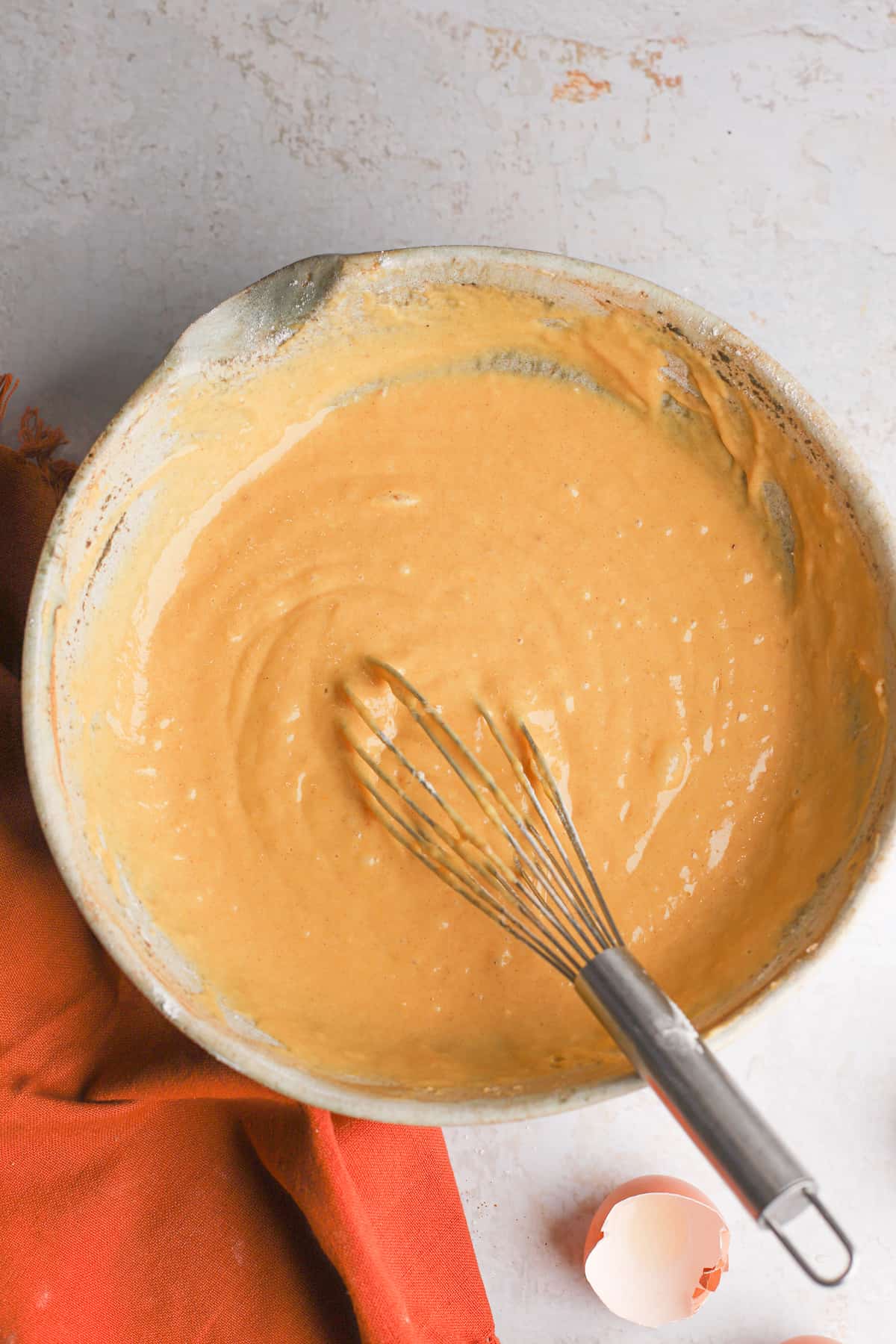 mixing bowl with a whisk and pumpkin bread batter