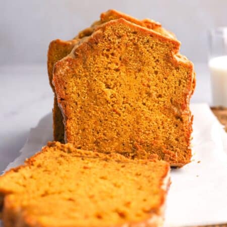 loaf of gluten free pumpkin bread on a platter with some slices lying down