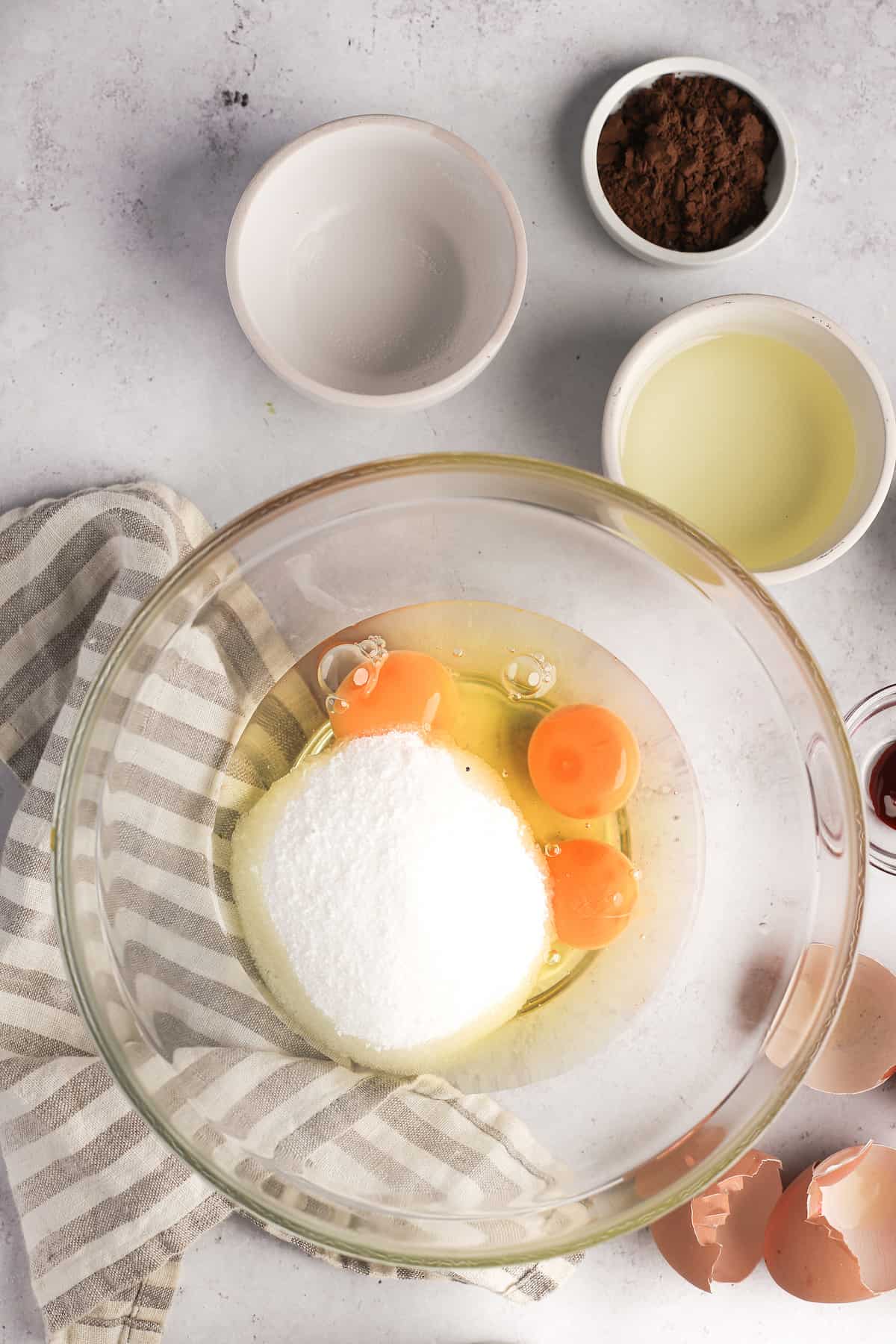 glass mixing bowl with eggs, flour sugar and oil
