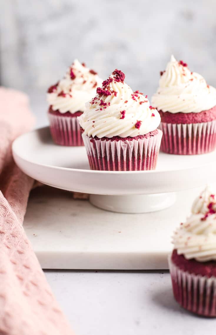 red velvet cupcakes with cream cheese frosting on a white cake stand