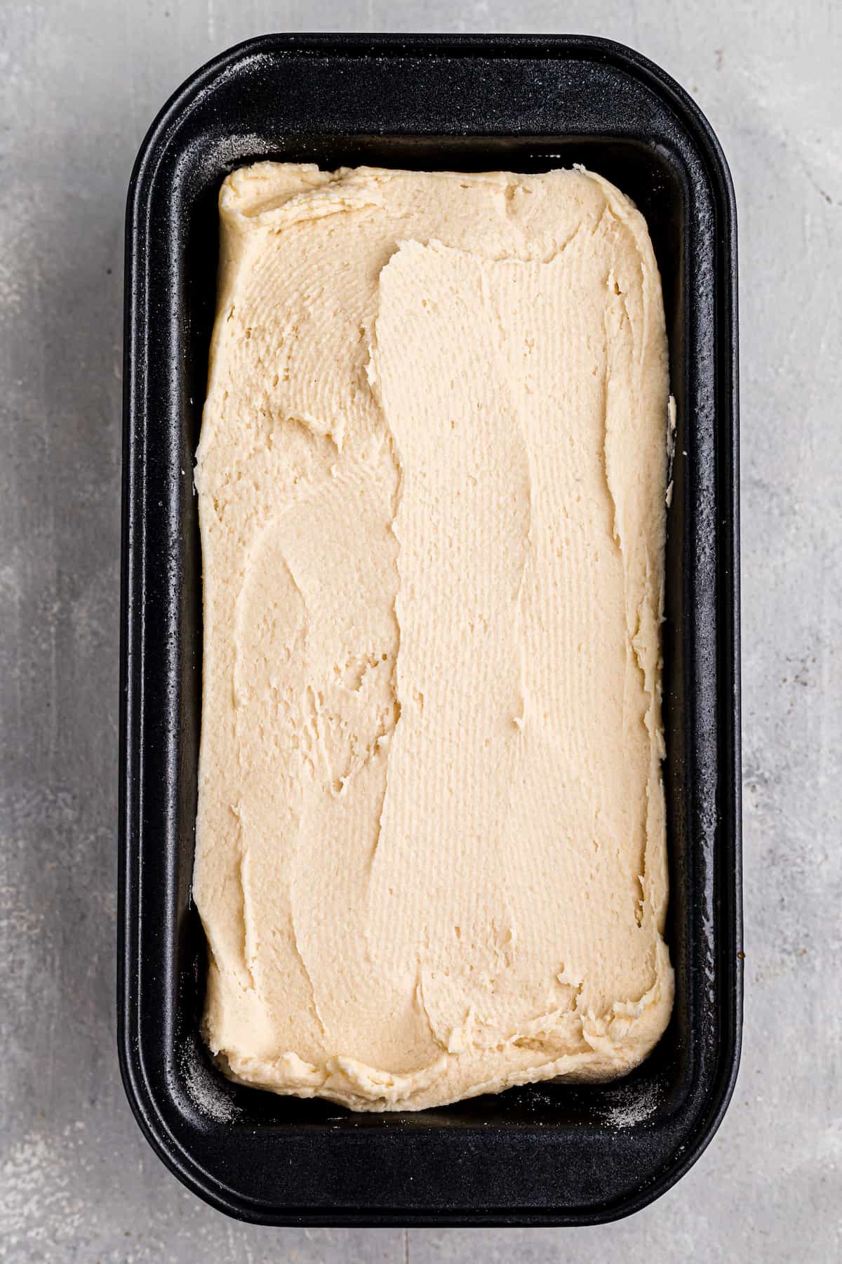 black loaf pan with bread dough