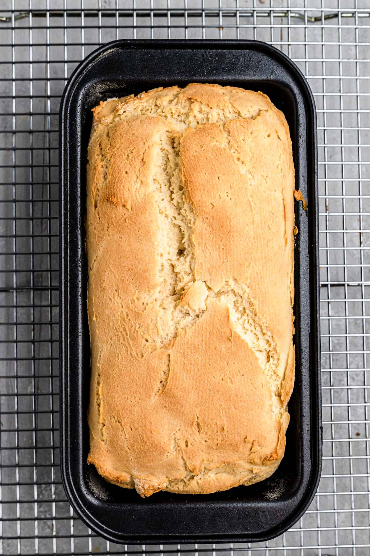 baked gluten-free sandwich bread in a loaf pan on a wire rack