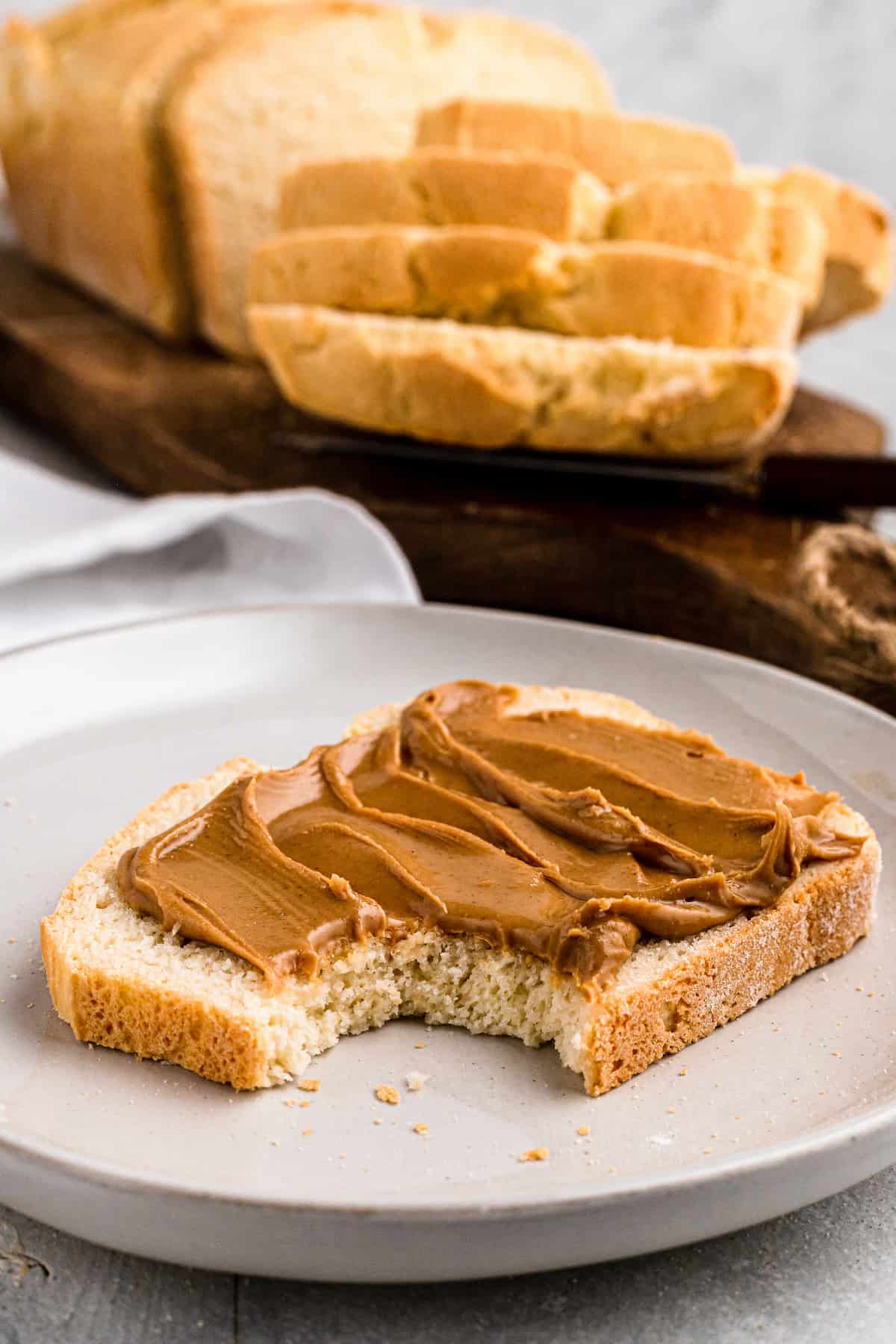 slice of sandwich bread with peanut butter on a plate