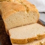 sliced loaf of gluten free sandwich bread on a wooden cutting board with two slices lying down