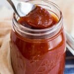 spooning bbq sauce out of a glass mason jar