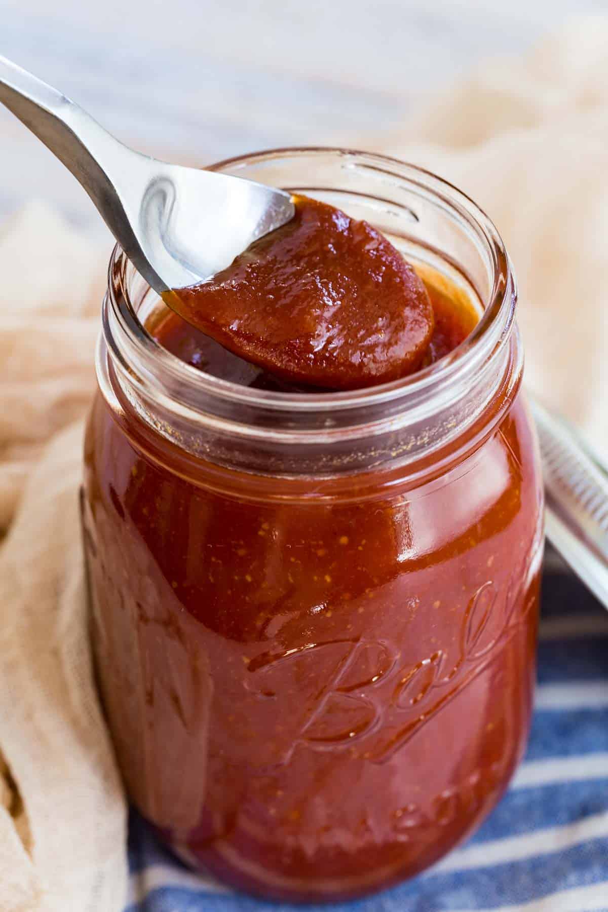 spooning bbq sauce out of a glass mason jar