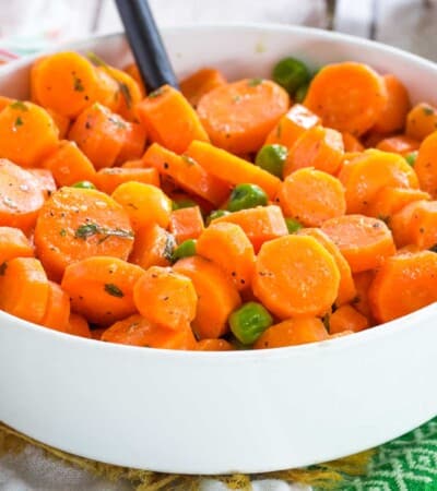 honey mustard carrots and peas in a white serving bowl