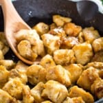 honey mustard chicken bites in a cast iron skillet with a wooden spoon