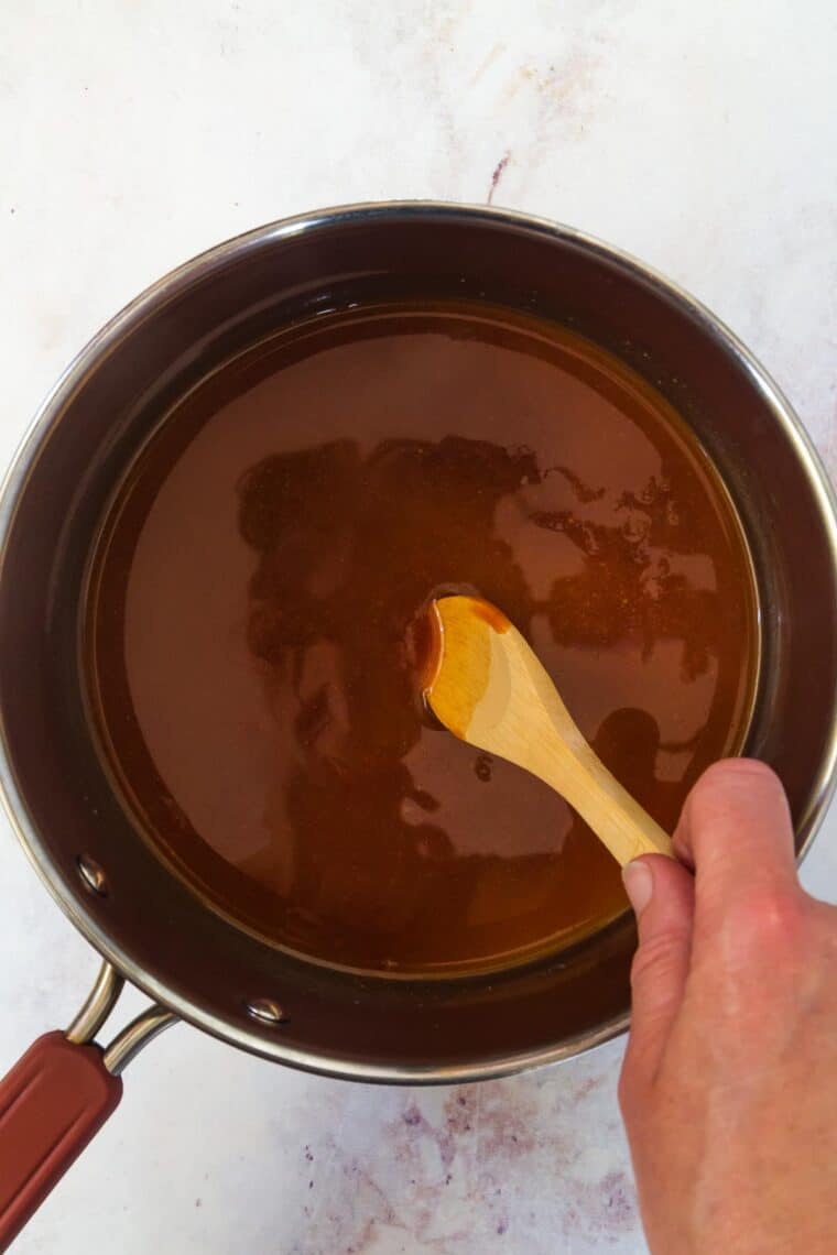 stirring barbecue sauce in a pot with a wooden spoon