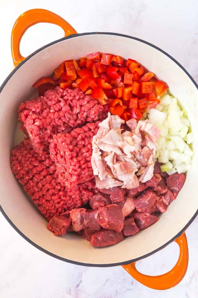 raw ground beef, stew meat, and bacon, plus chopped onion and red pepper in a large pot