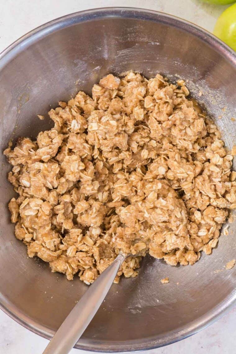 the oat topping for a fruit crisp in a silver mixing bowl with a fork