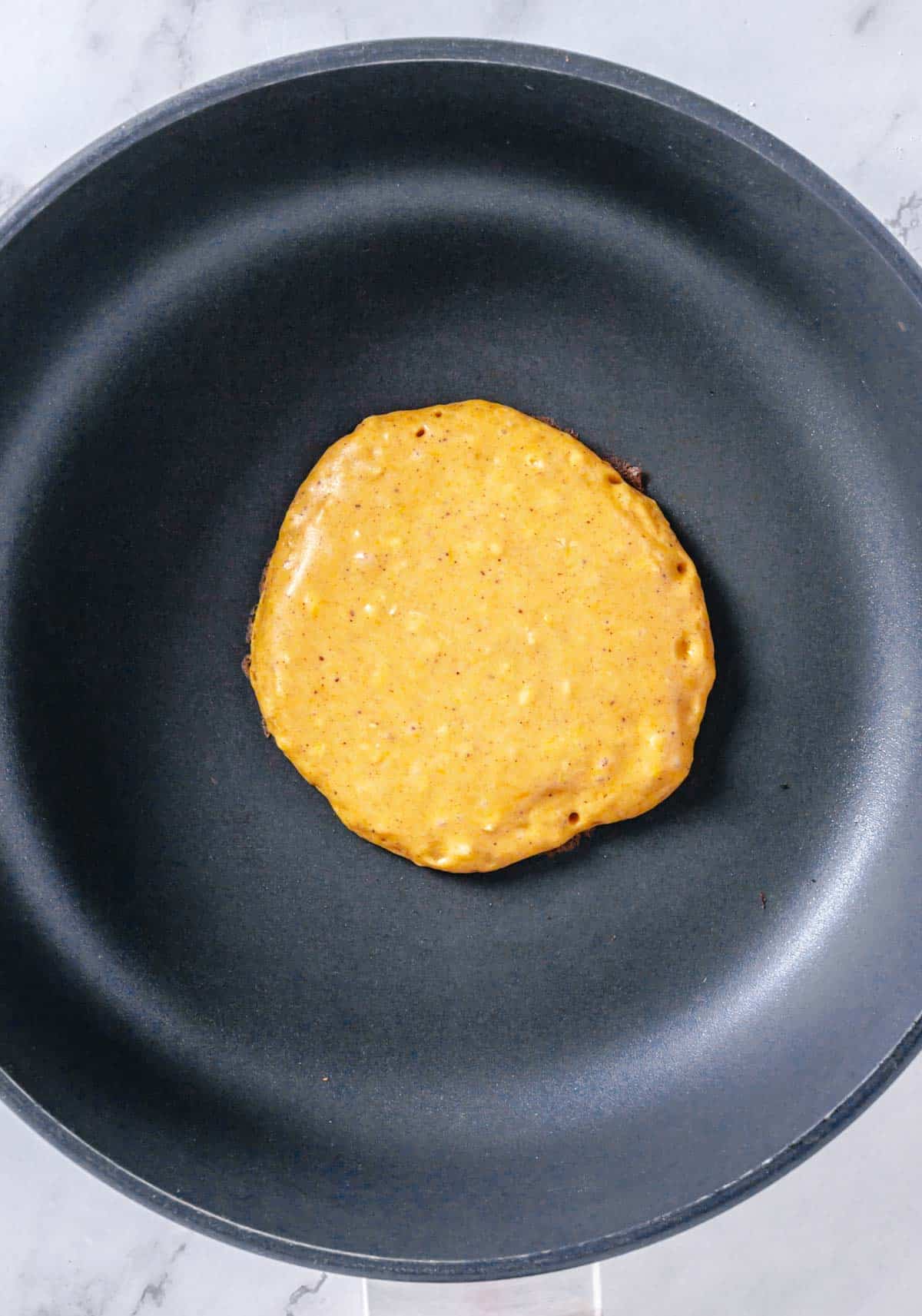pumpkin pancake cooking in a skillet
