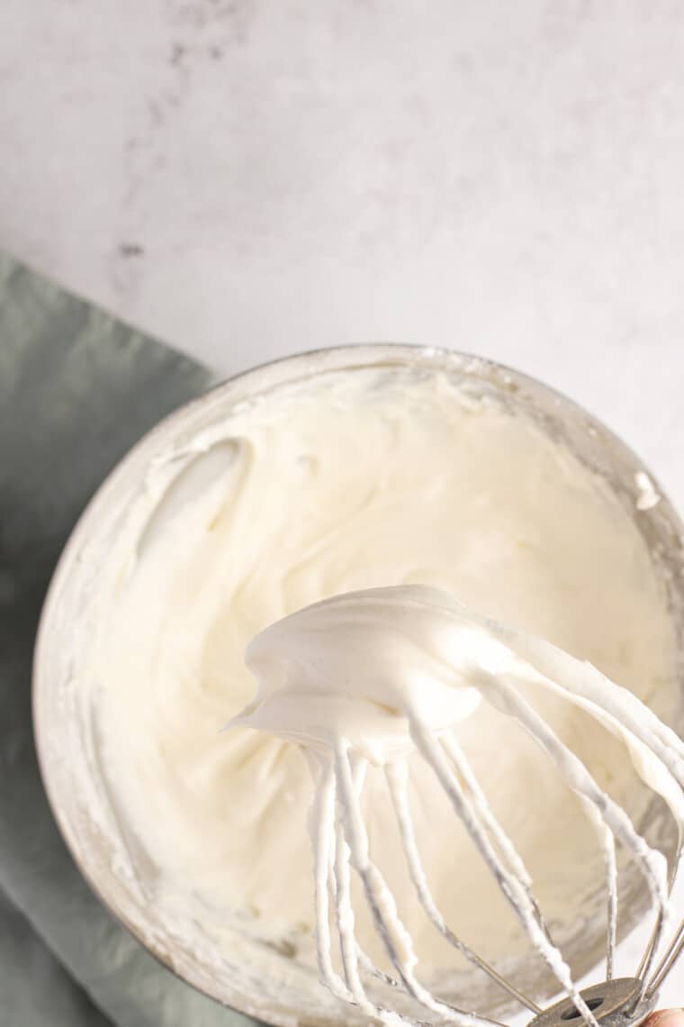 whisk with vanilla cream cheese frosting over a mixing bowl