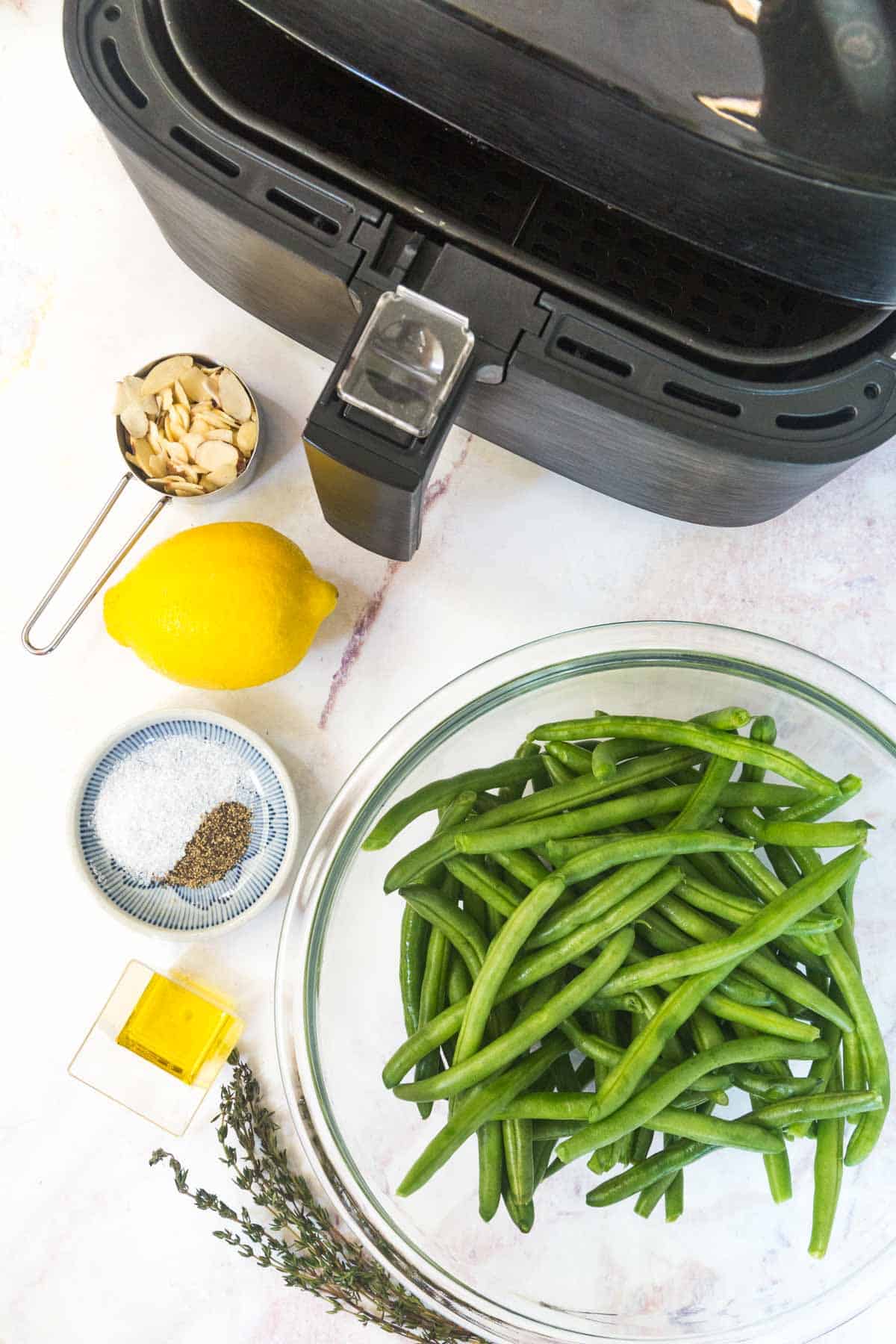 fresh green beans lemon, ,and almonds next to an air fryer