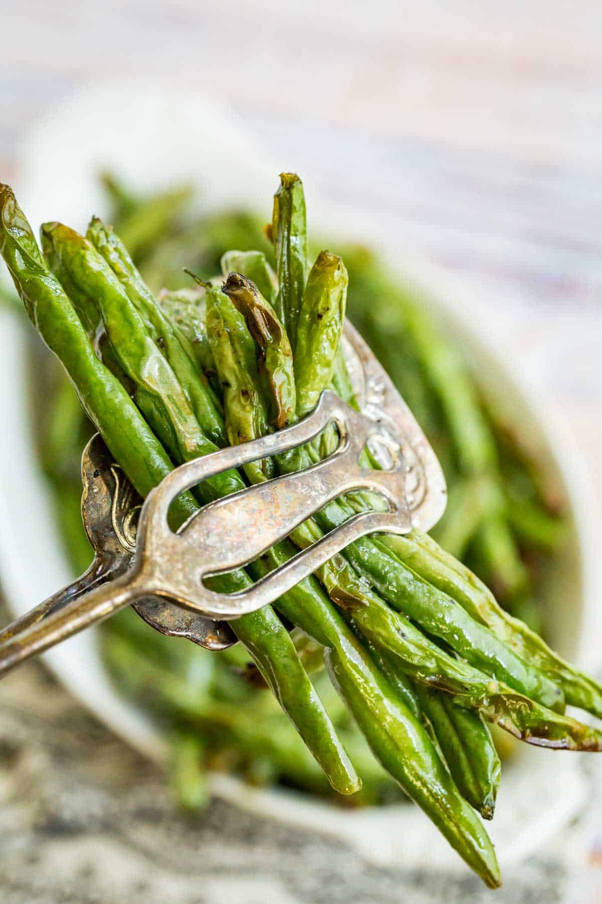 tongs holding a bundle of cooked green beans