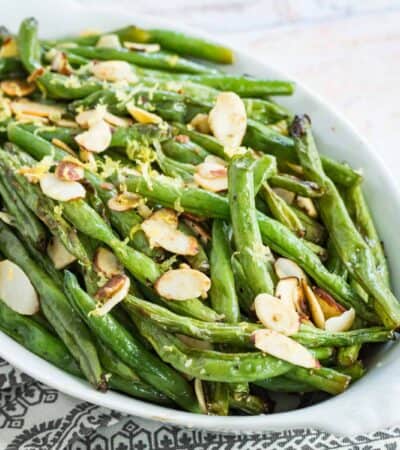 air fryer green beans with sliced almond and lemon zest in a white serving dish