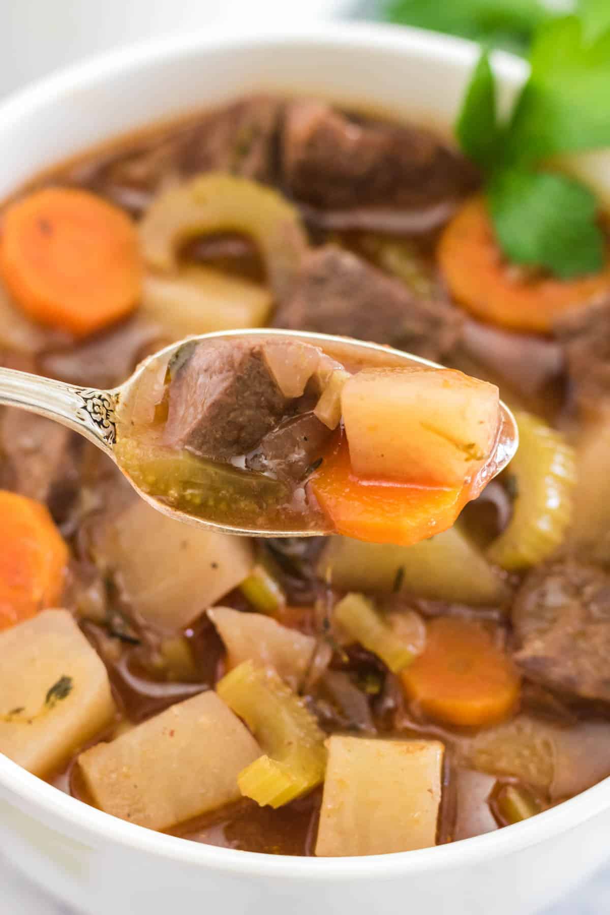 spoonful of crock pot beef stew over a bowl of stew