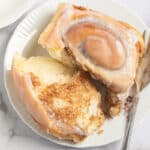 gluten free cinnamon roll on a plate with one side torn off