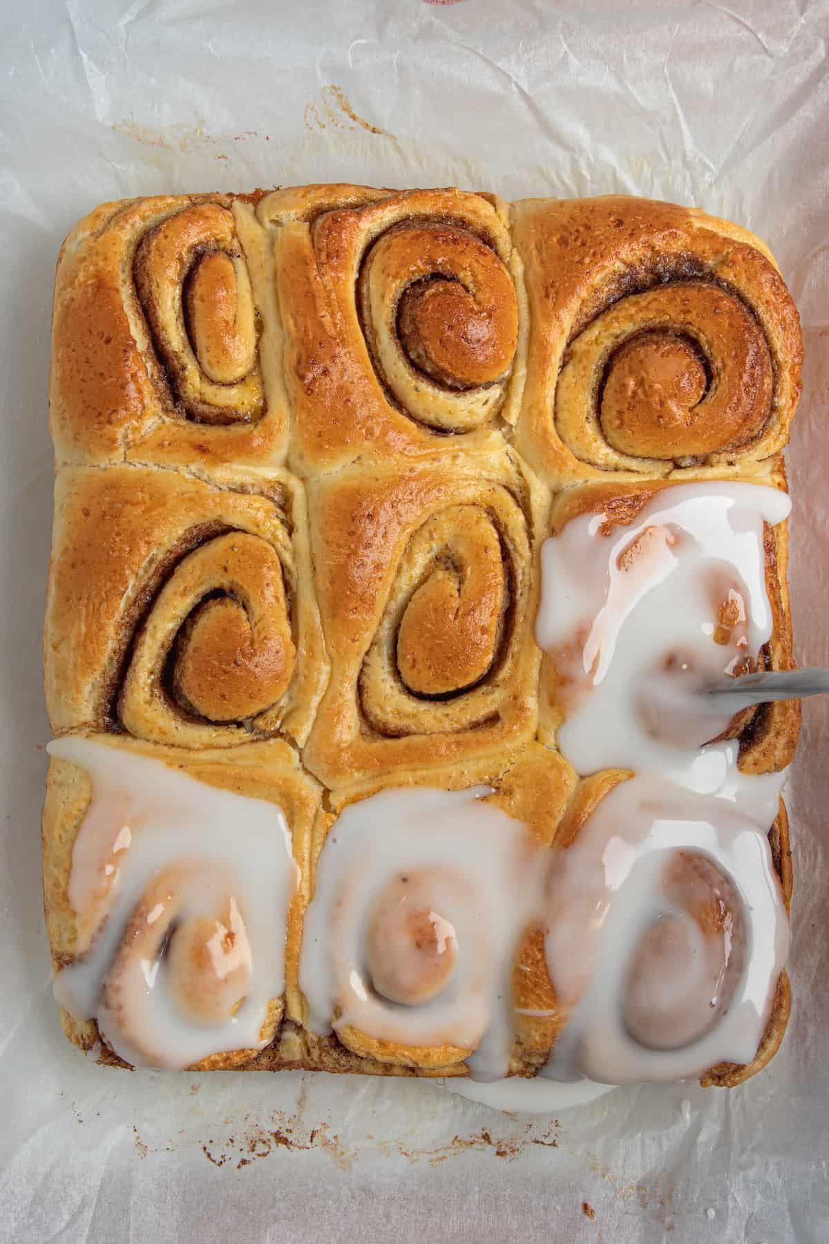 pouring glaze on cinnamon rolls