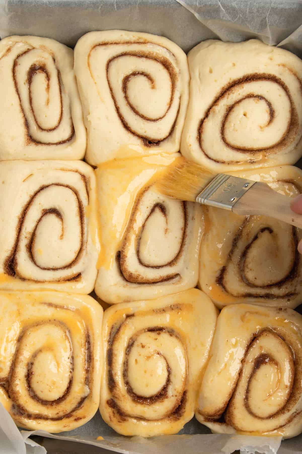 brushing cinnamon buns with butter