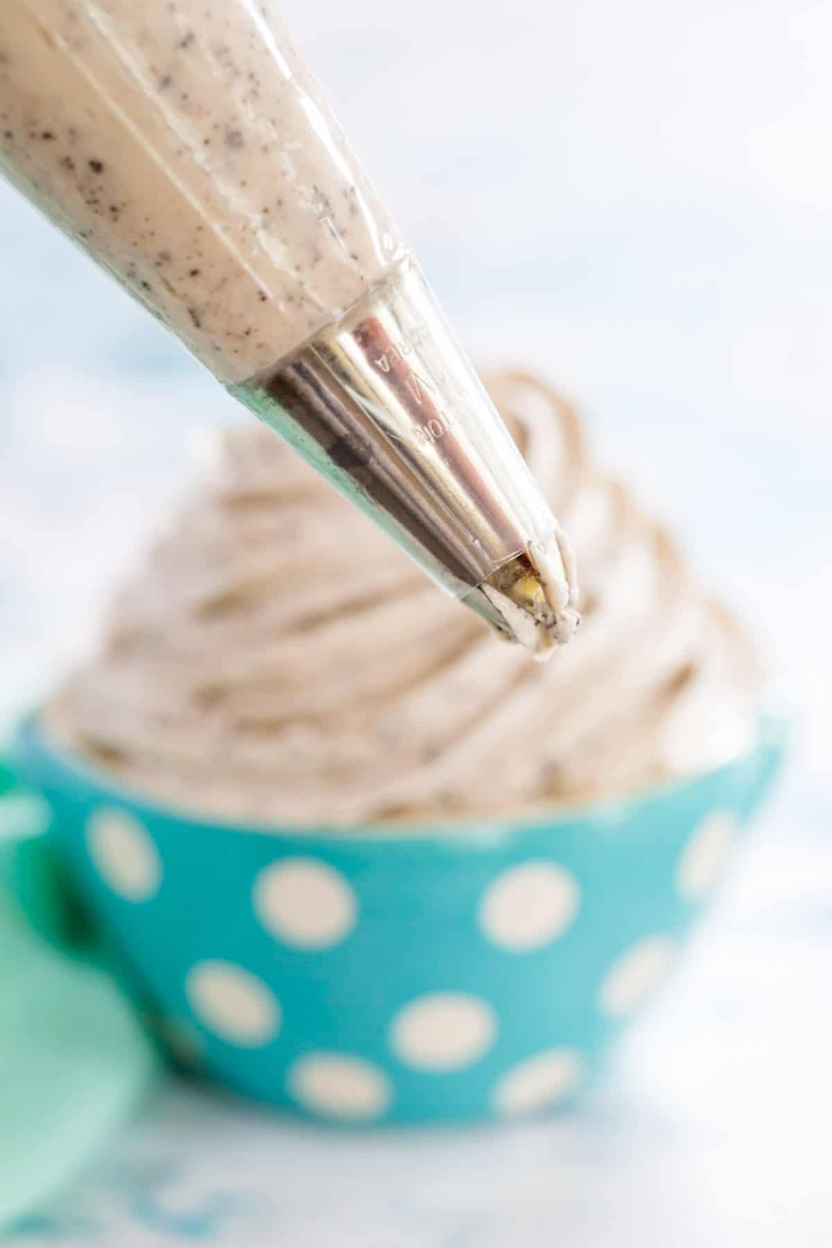 Frosting flecked with cookie bits in a plastic piping bag fitted with a Wilton 1M star tip.