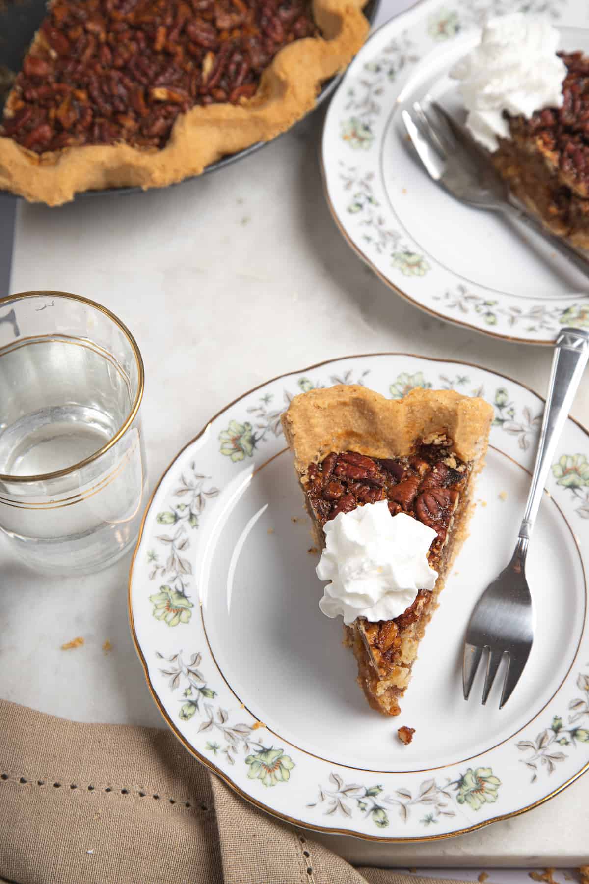 slices of pecan pie on plates with whipped cream