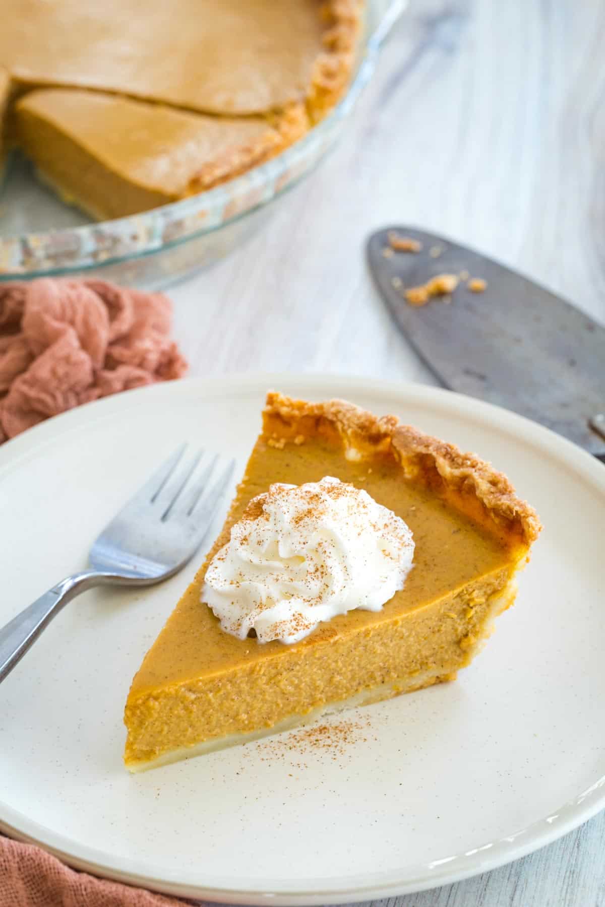 Gluten free pumpkin pie on a white plate with whipped cream