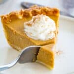 for cutting off a bit of a slice of gluten free pumpkin pie topped with whipped cream