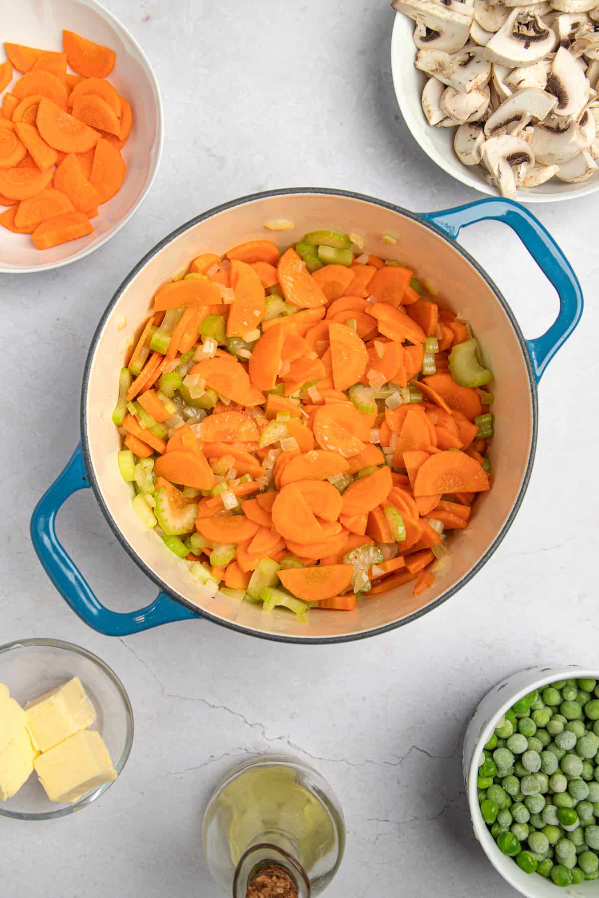 cooking carrots, celery and onions in a blue pot