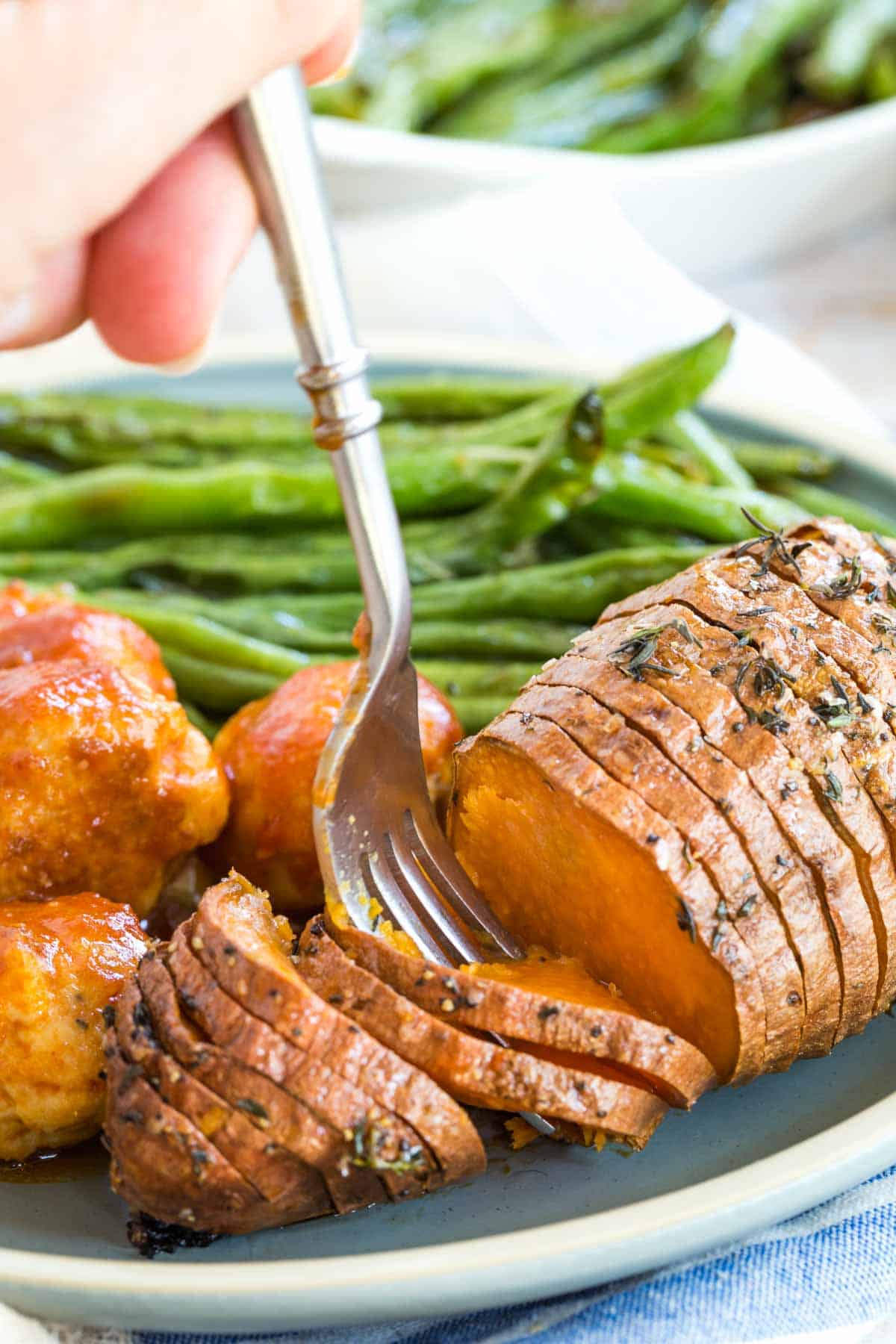 cooked sweet potato on a plate with meat balls and green beans