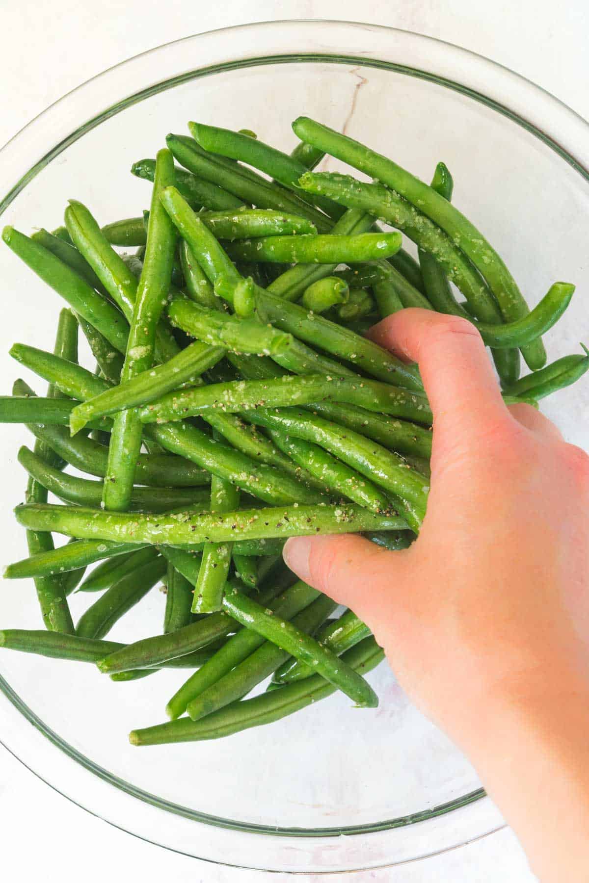 tossing green beans with salt and pepper