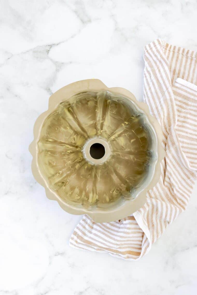 a greased bundt cake pan on top of a striped cloth napkin