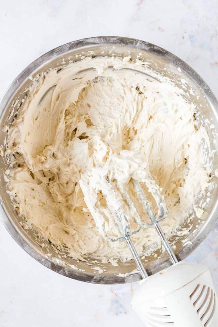 hand mixer set above a bowl of vanilla buttercream frosting