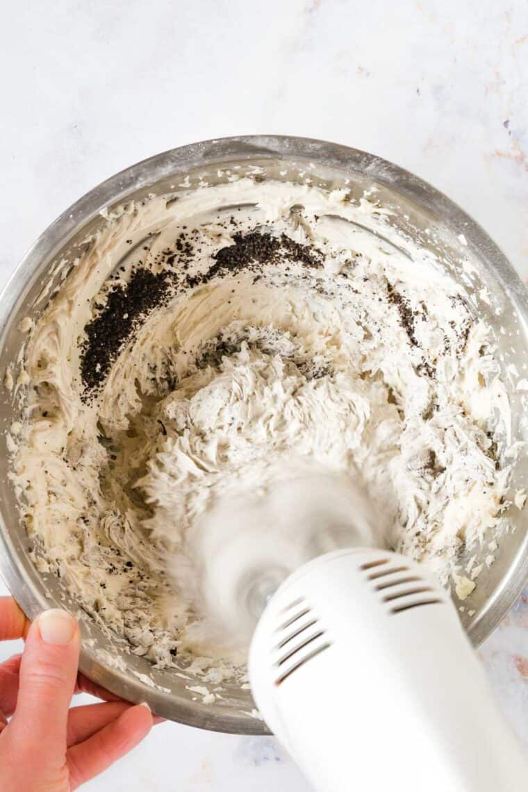 hand mixer beating oreo crumbs into the frosting