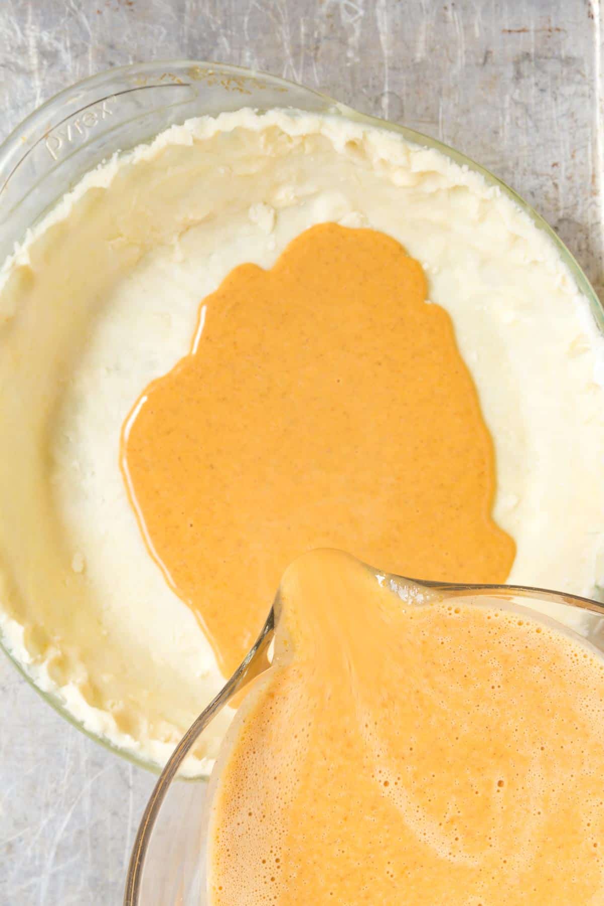 pouring pumpkin filling into a pie crust