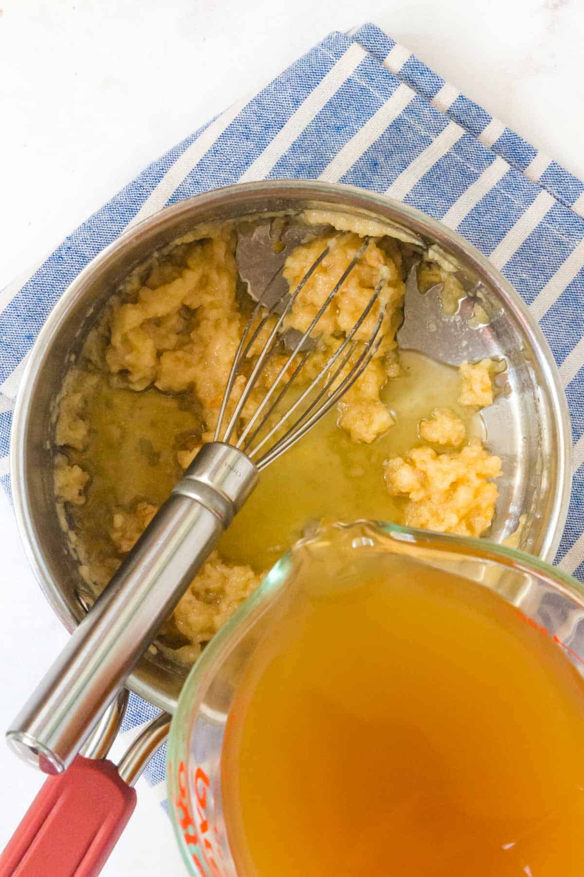 adding stock to a roux in a saucepan